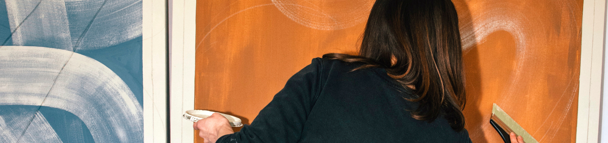 Cat Spilman painting a large abstract artwork on a wall.