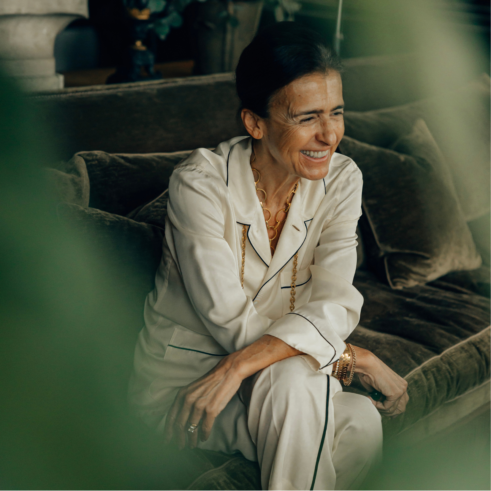 Woman in white pajamas sitting on a couch, smiling.