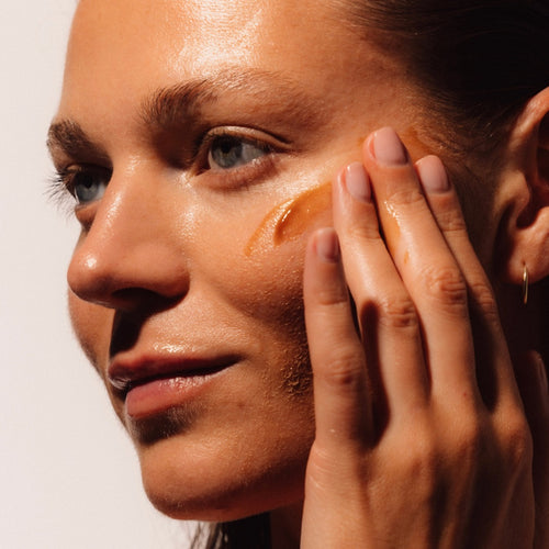 Close-up of a woman applying a LAST Cleansing Gel to her face.