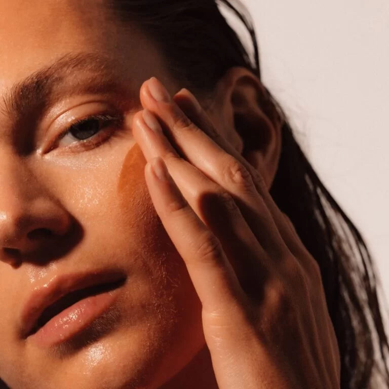 Close-up of a person applying LAST Skin Repair Serum to their face with a hand.
