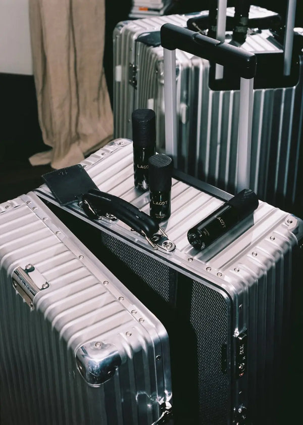 Silver suitcases with black LAST skincare bottles on a dark floor.