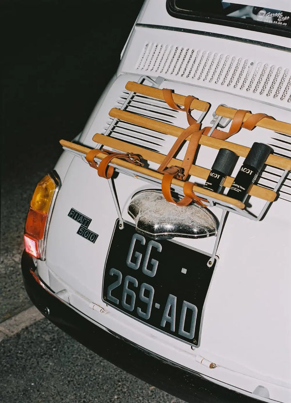 Back of a white car with a luggage rack, LAST Skincare products and a license plate.